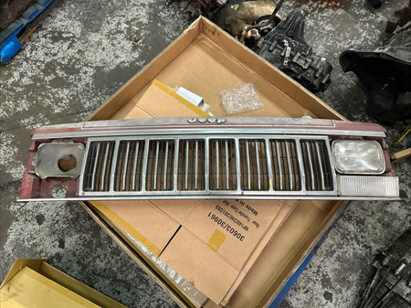 Jeep Comanche grill featuring distinct grill bars and headlight area, presented on a box background.
