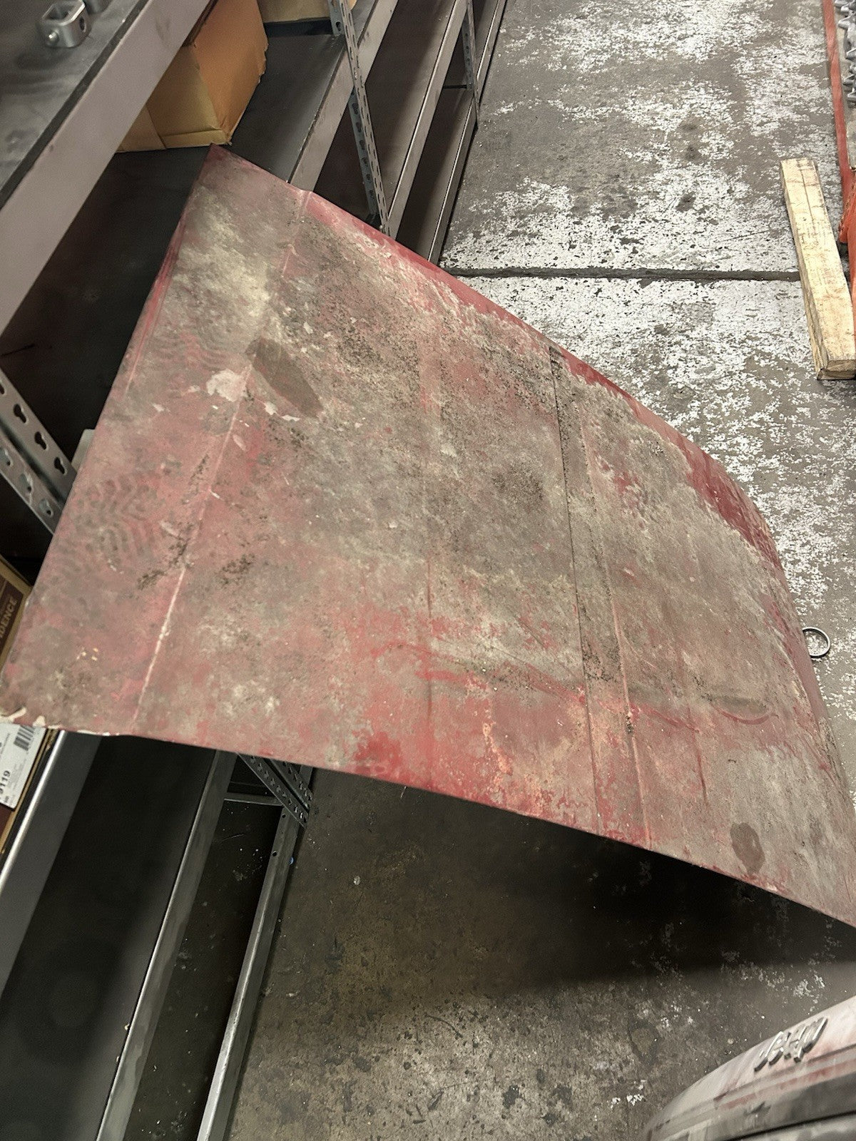 Used Jeep Cherokee Hood with dirt on surface, displayed on a shelf in a garage setting.